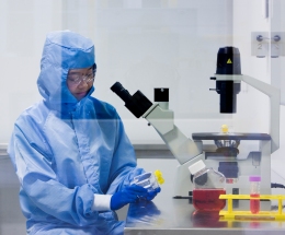 Researcher wearing a clean room suit in the cell therapy manufacturing lab. 