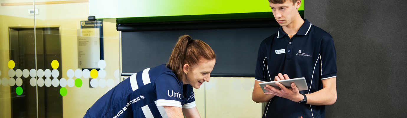 An athlete training on an exercise bike while a researcher watches