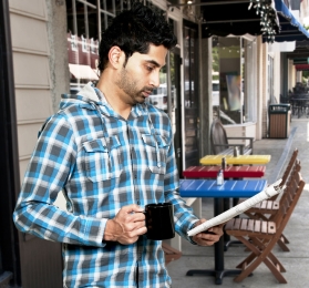 Young Muslim man reading a newspaper