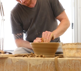 Man making a clay bowl in a potter's studio