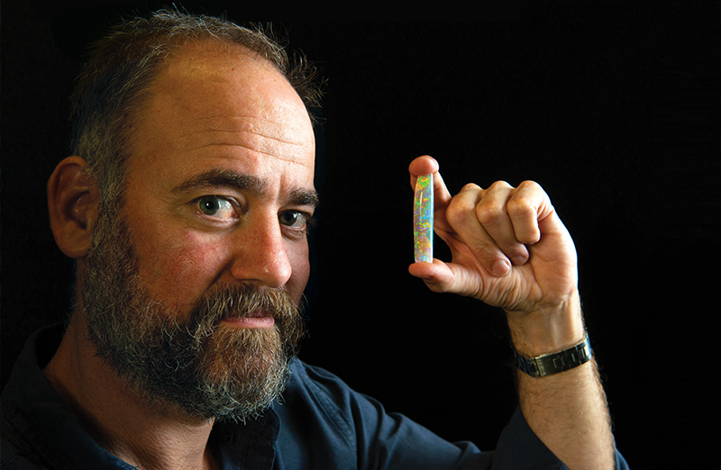 Tim Gilchrist Tim Gilchrist with the Virgin Rainbow, the world’s most expensive opal. The opalised ‘pen’ of an extinct species of cuttlefish, called Belemnite, is said to glow in the dark. Photo by Brenton Edwards.