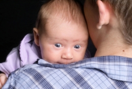 Baby looking over person's shoulder. 