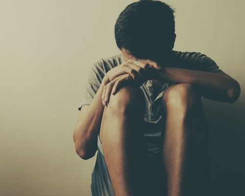 Young man crouching with his head in his hands