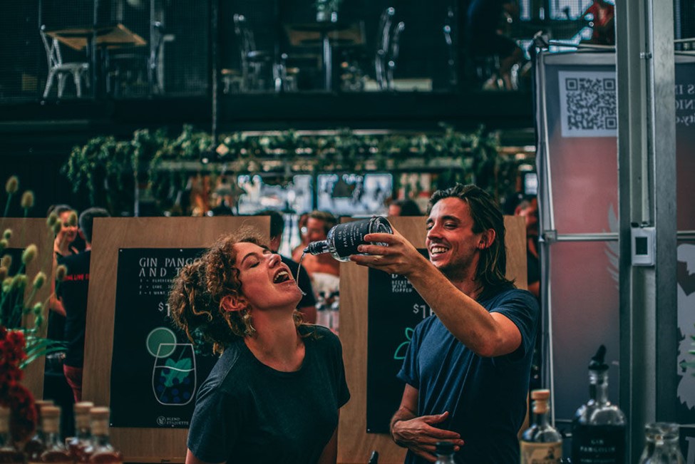 Bartender pouring gin into colleagues mouth