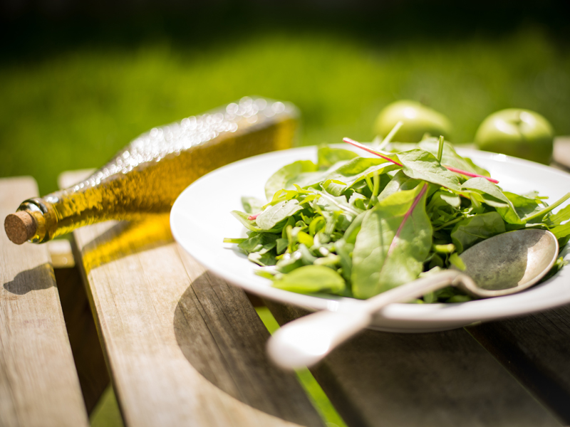 Leafy greens in a bowl on a wooden slat table