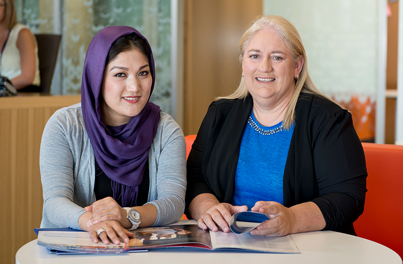 Two women at a table with an open brochure