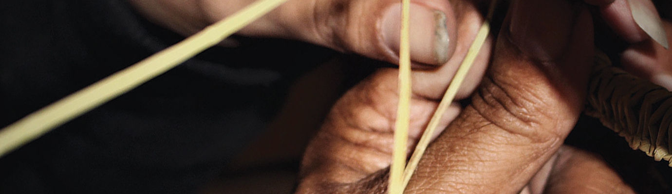 Weathered hands weaving a basket