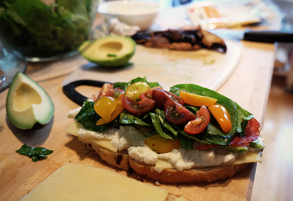 Bread topped with hommous, cheese, avocado, capsicum, spinach and tomato