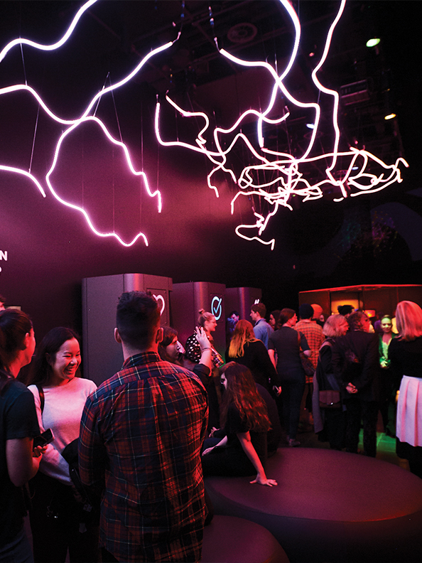 A crowd of people in the MOD.space under pink neon lights