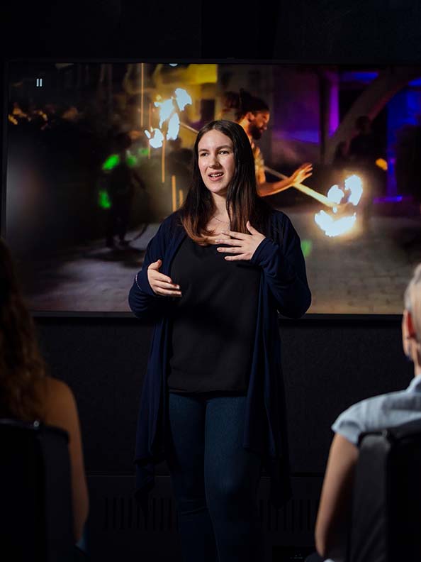 A woman speaking to an audience in front of a projector screen