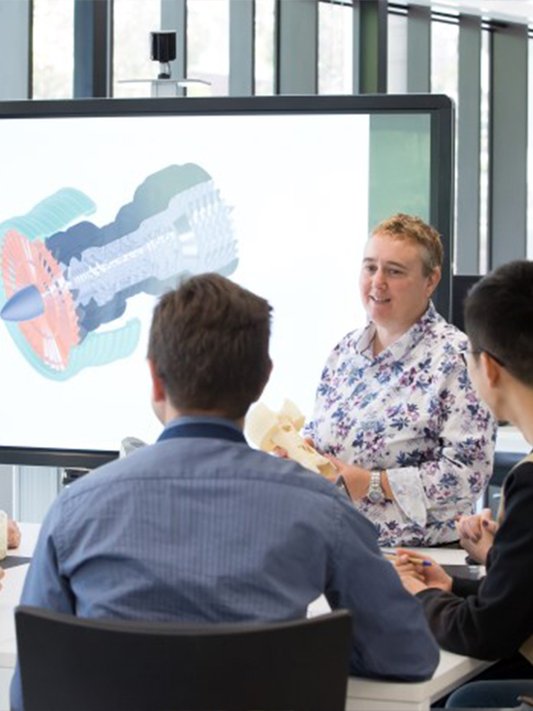 Students sitting around a screen displaying engineering diagrams