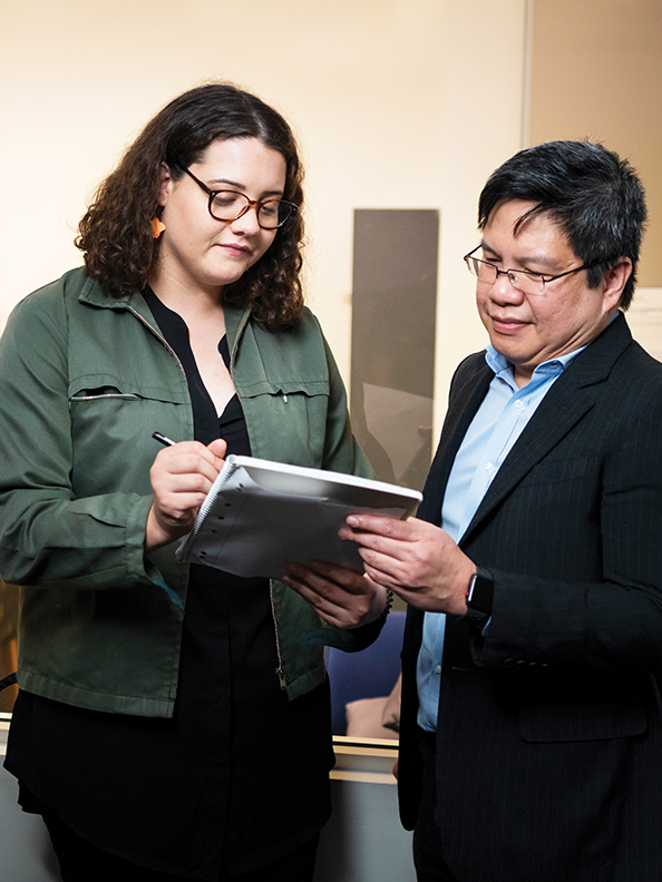 Two people consulting a notebook