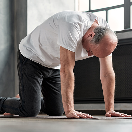 Older man stretching back in cat yoga pose