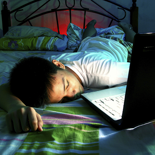boy asleep on bed with computer