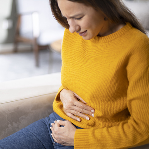 sitting woman holding her tummy in pain