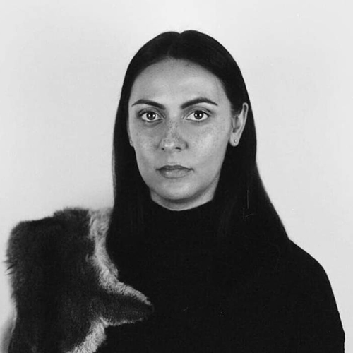 Black and white portrait of Hayley Millar Baker, an Aboriginal woman with long, dark, strait hair wearing a black top and animal skin draped over her right shoulder.jpg