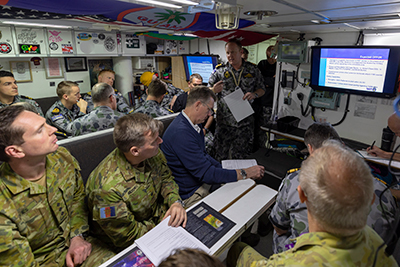 HMAS Farncomb executive officer Lieutenant Commander Benjamin Sweetenham presents an inshore operations brief to guests and crew aboard HMAS Farncomb in Sydney. Photo by Royal Australian Navy.