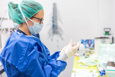 Female nurse puts on protective gloves and face mask